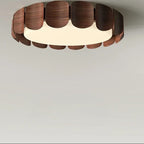 Circular flush ceiling light with scalloped wood segments and bright white glow