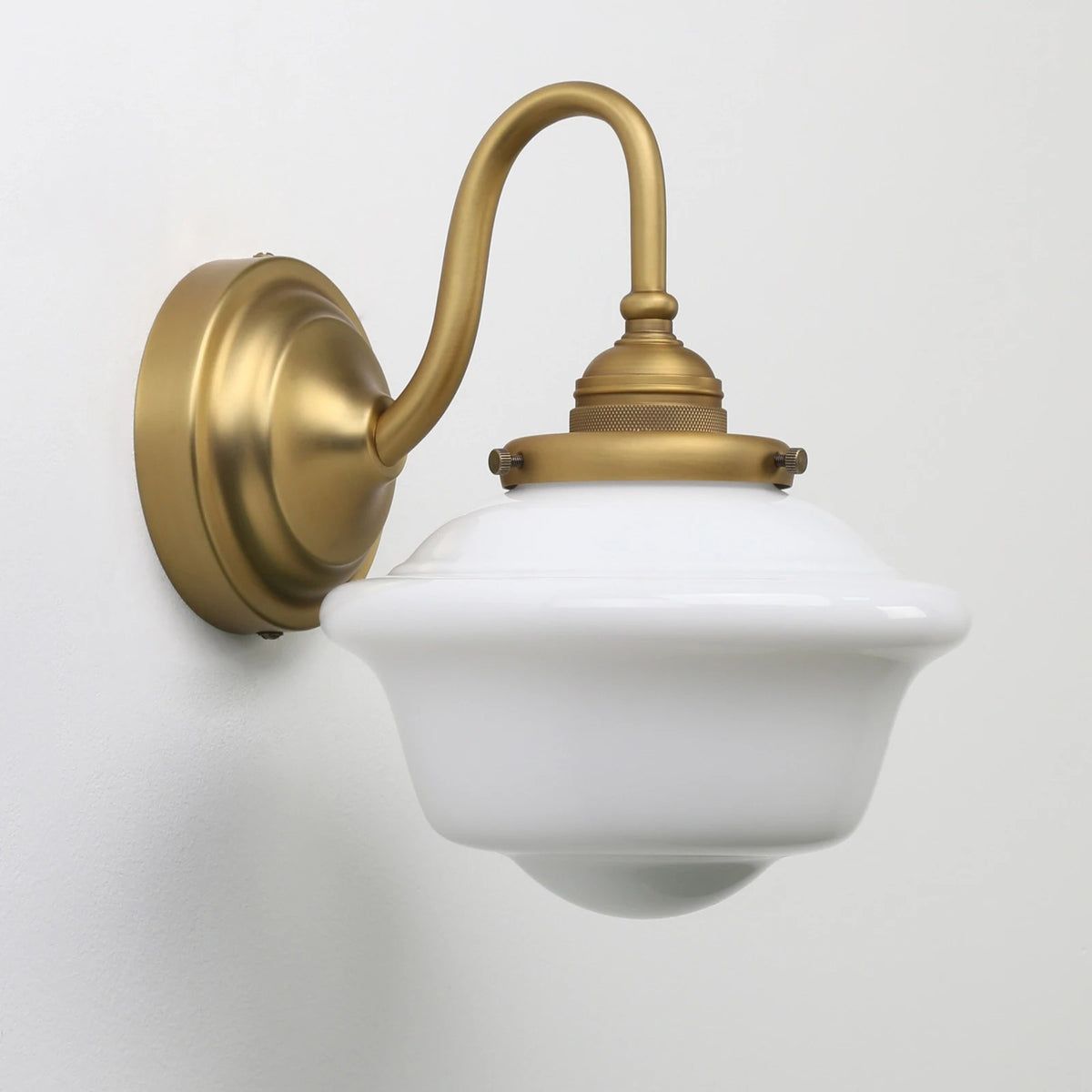 Antique brass wall sconce with frosted dome shade and curved wall mount