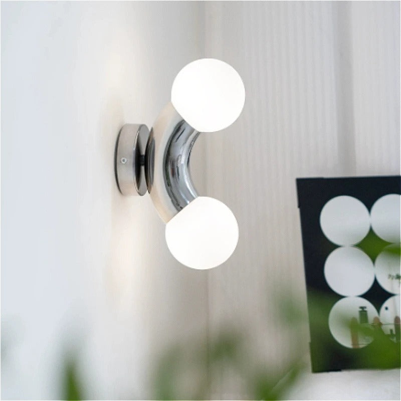 Chrome wall light with two frosted globe shades on a curved metal arm