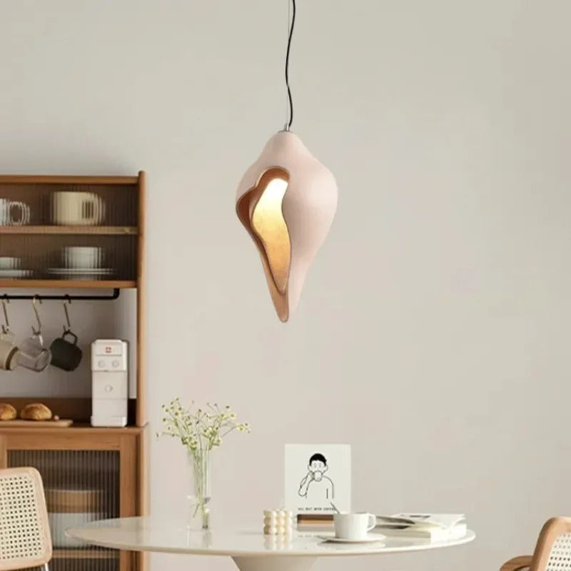 Conch shell pendant light with white shell and glowing gold interior on hanging cord