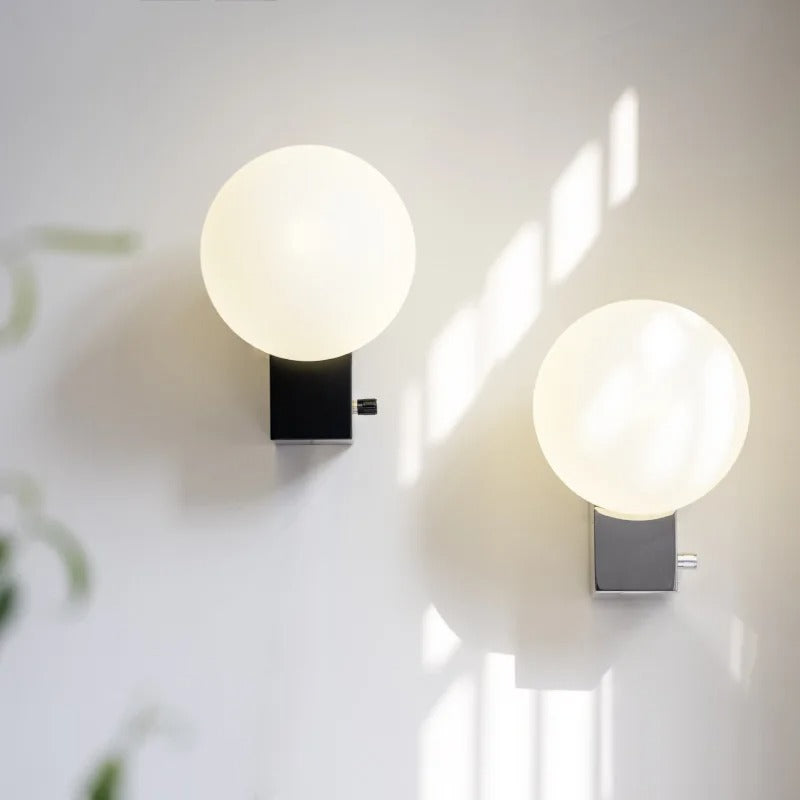 Spherical globe wall light with black rectangular backplate and frosted white globe, lit