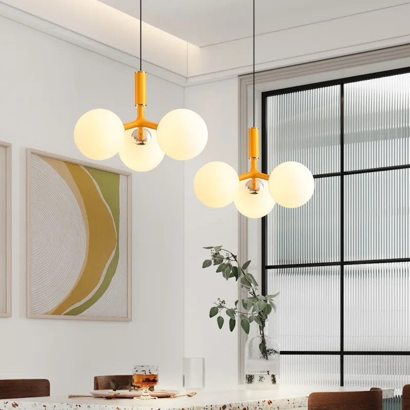 Yellow globe pendant light with five round glass shades and chrome mounting