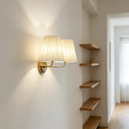 Gold-tone twin wall sconce with two pleated shades and wall-mounted arm