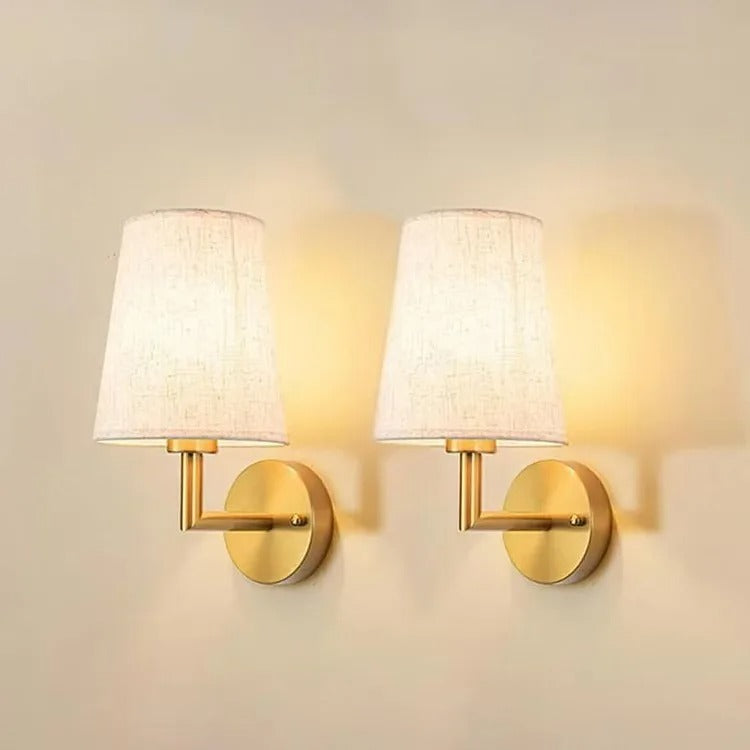Pair of conical fabric wall lights with gold round backplates and metal arms