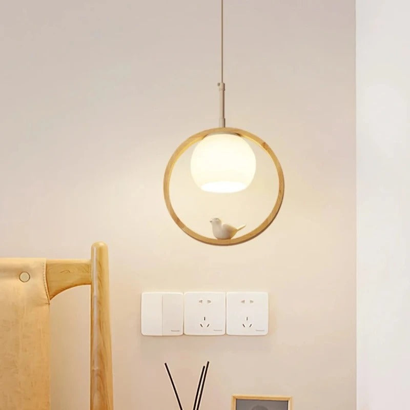 Wooden ring pendant light with bird figure, hanging with warm glowing bulb.