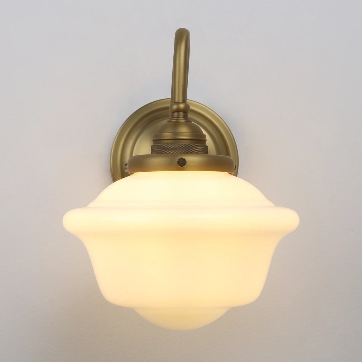 Antique brass wall sconce with frosted dome glass shade and arched stem