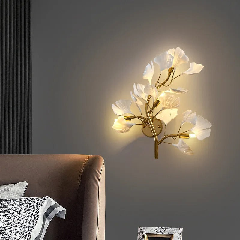 Botanical branch wall sconce with glowing off-white leaf shades and gold base