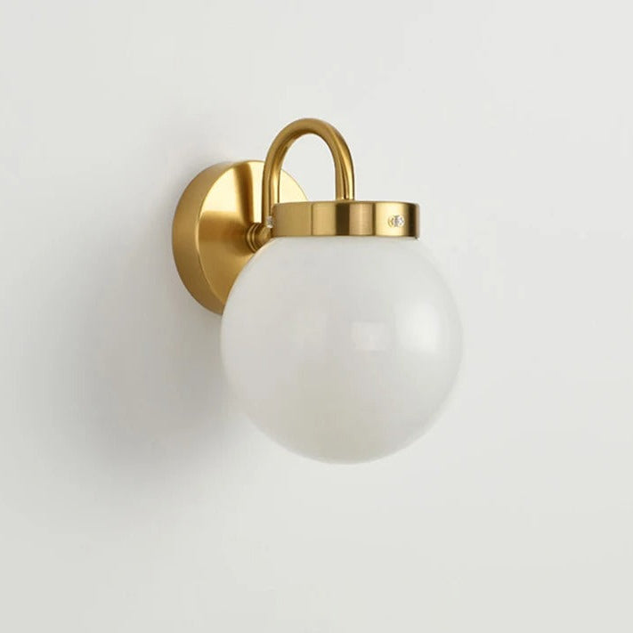Gold curved-arm globe wall light with round glass shade