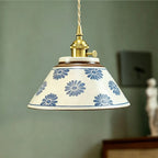 Ceramic conical pendant light with blue daisy floral pattern shade and brass hardware