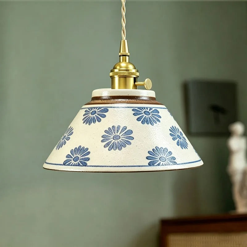 Ceramic conical pendant light with blue daisy floral pattern shade and brass hardware