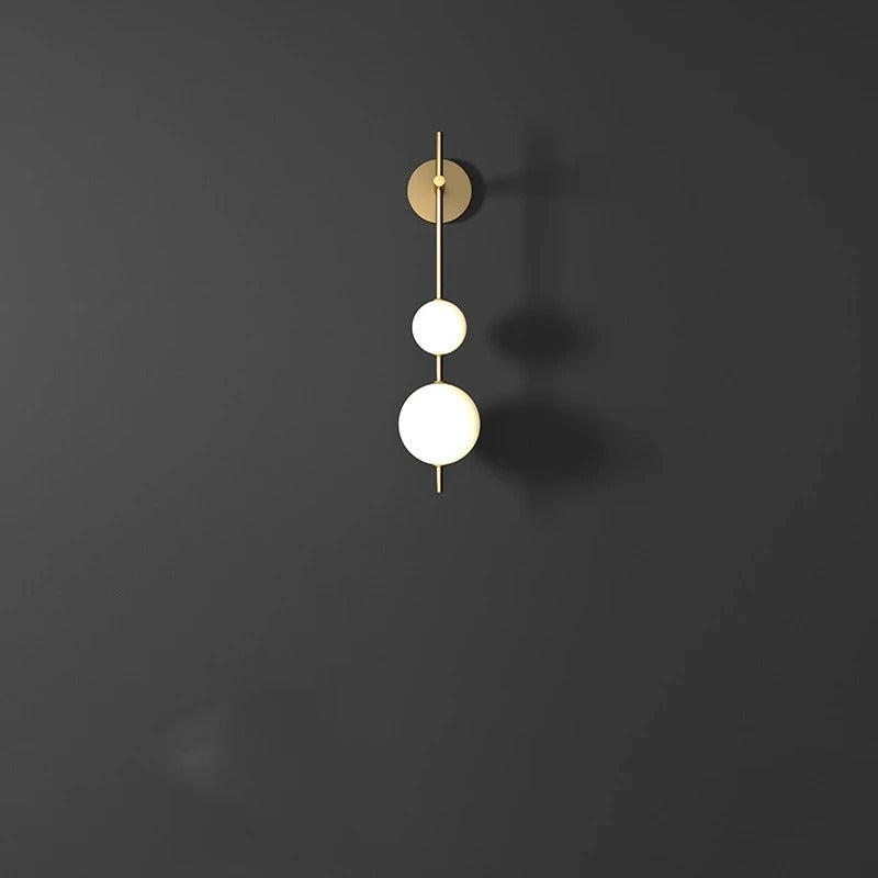 Brass wall sconce with three stacked white globe shades