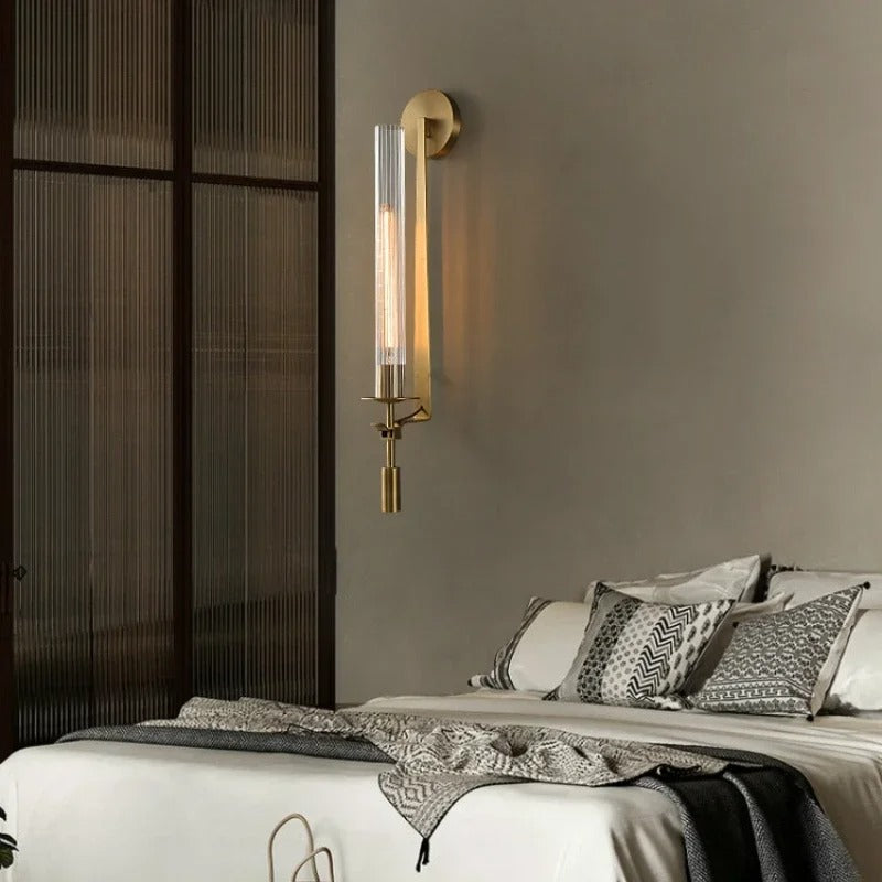 Gold vertical tube wall sconce with glass cylinder and small metal finial