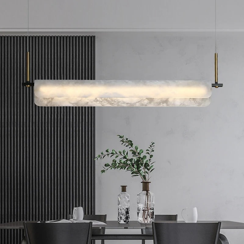 Rectangular linear alabaster bar chandelier with glowing white diffuser over dining table