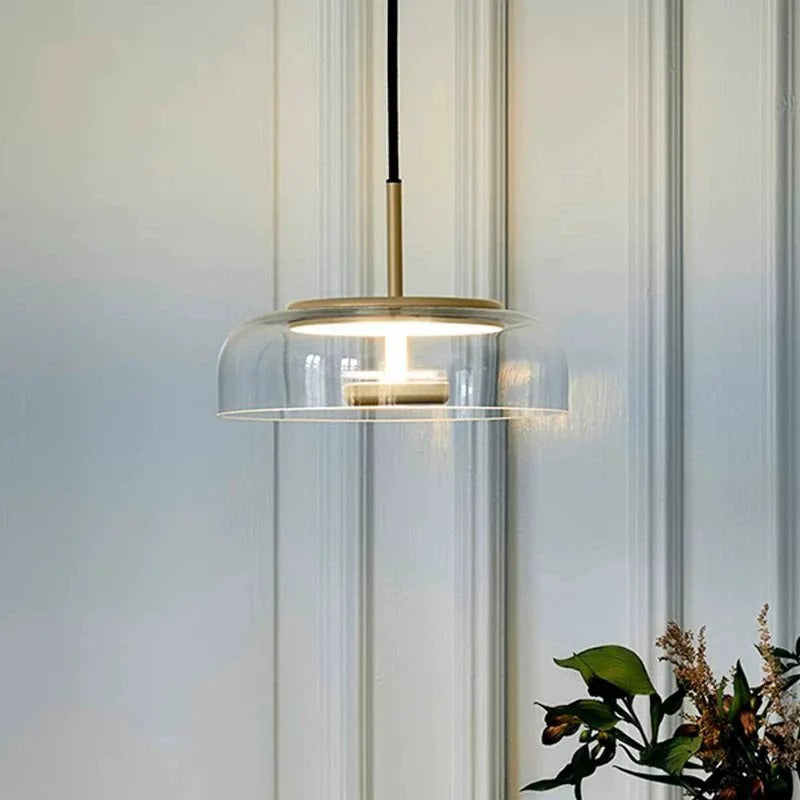 Clear glass dome pendant light with black cord and gold ceiling plate, warm bulb lit