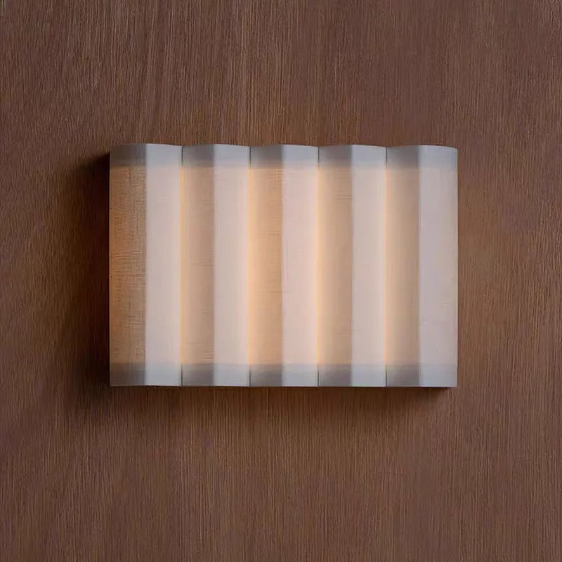Wall sconce with curved tiered shade and glowing diffuser bars