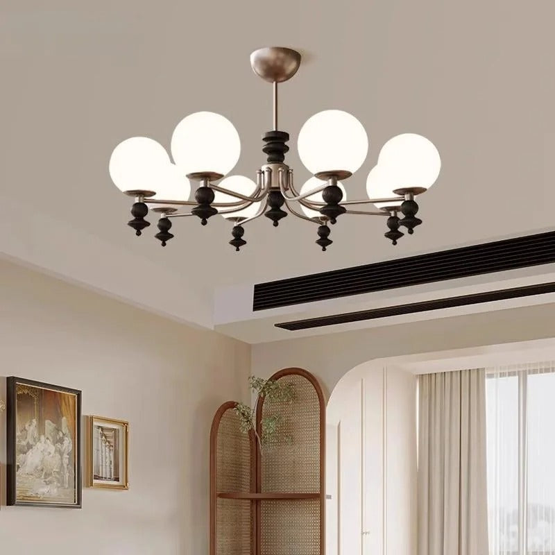 Multi-arm globe chandelier with curved arms and white glass globes in bronze finish