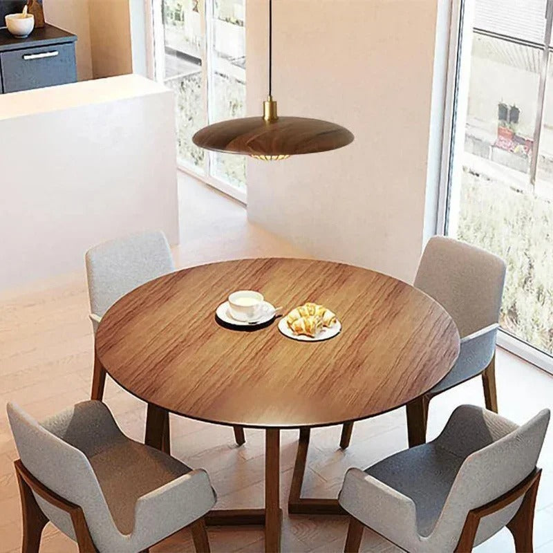 Round wood disc pendant light with central stem, hanging over a table