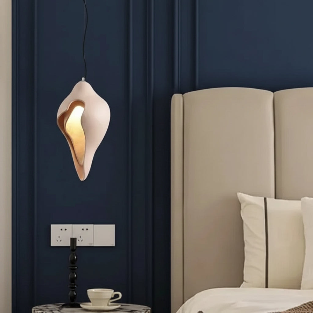 Conch shell pendant light in white with glowing gold interior on hanging cord
