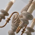 Close-up of spindle chandelier scroll arms and candle-style bulbs in bronze