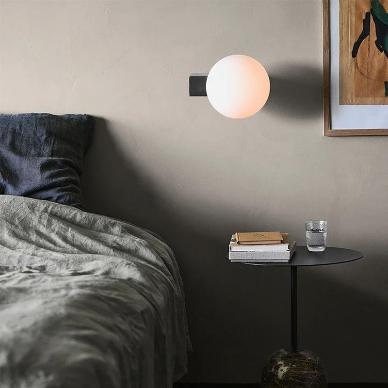 Spherical globe wall light on black wall mount with frosted white globe, warm wall glow