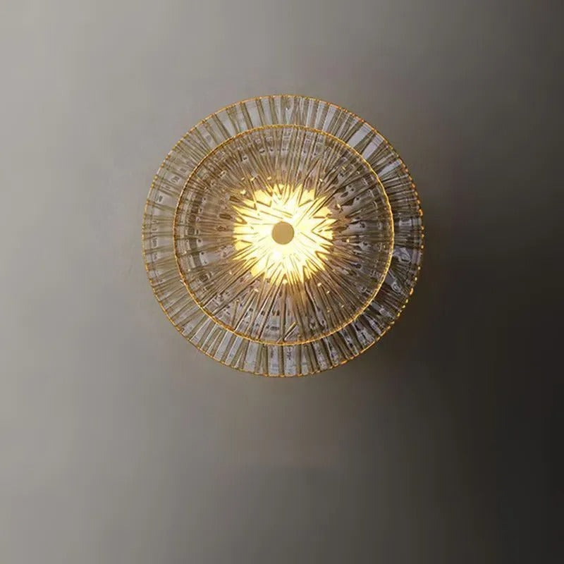 Tiered circular glass wall light with bright warm center and gold-toned ring