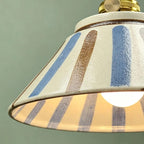 Ceramic conical pendant light close-up with blue and brown vertical stripe pattern