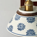 Ceramic conical pendant light close-up with blue daisy floral pattern shade and brass top