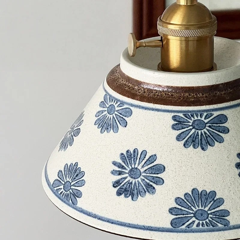 Ceramic conical pendant light close-up with blue daisy floral pattern shade and brass top