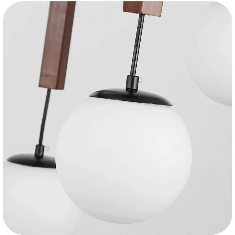 Hanging globe shade with black top cap under a walnut chandelier frame