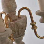 Close-up of rustic chandelier spindle arms with bronze finish and scroll details