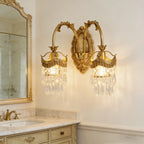 Gold crystal wall sconce with ornate curved arms and two hanging crystal shade clusters