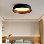 Black shallow dome ceiling light with wood-toned base and warm inner glow