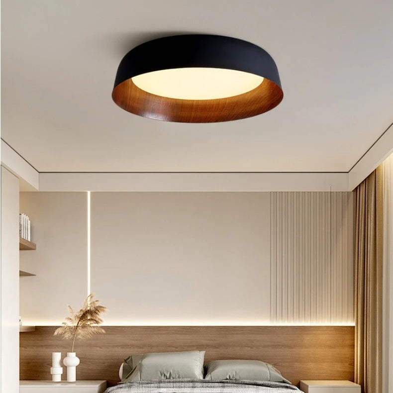 Black shallow dome ceiling light with wood-toned base and warm inner glow