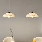 Pair of alabaster domed pendant lights with black cords and round shades