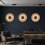Set of three round backlit wall lights with textured stone discs and dark centers
