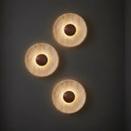 Three round backlit wall sconce discs with textured finish and dark glowing center