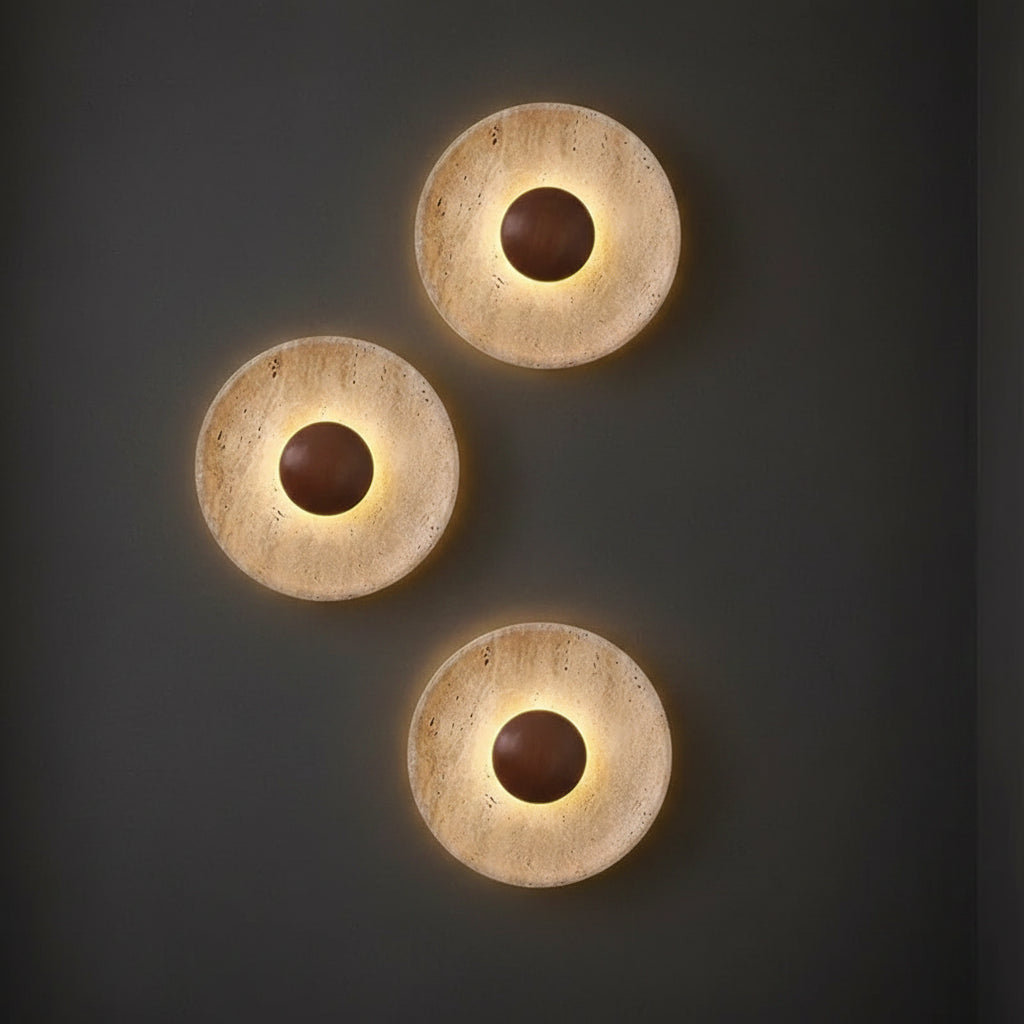 Three round backlit wall sconce discs with textured finish and dark glowing center