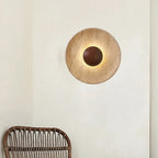 Round backlit wall light with textured tan disc and dark center aperture