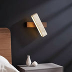 Long bar wall sconce light with speckled travertine panel and warm LED glow