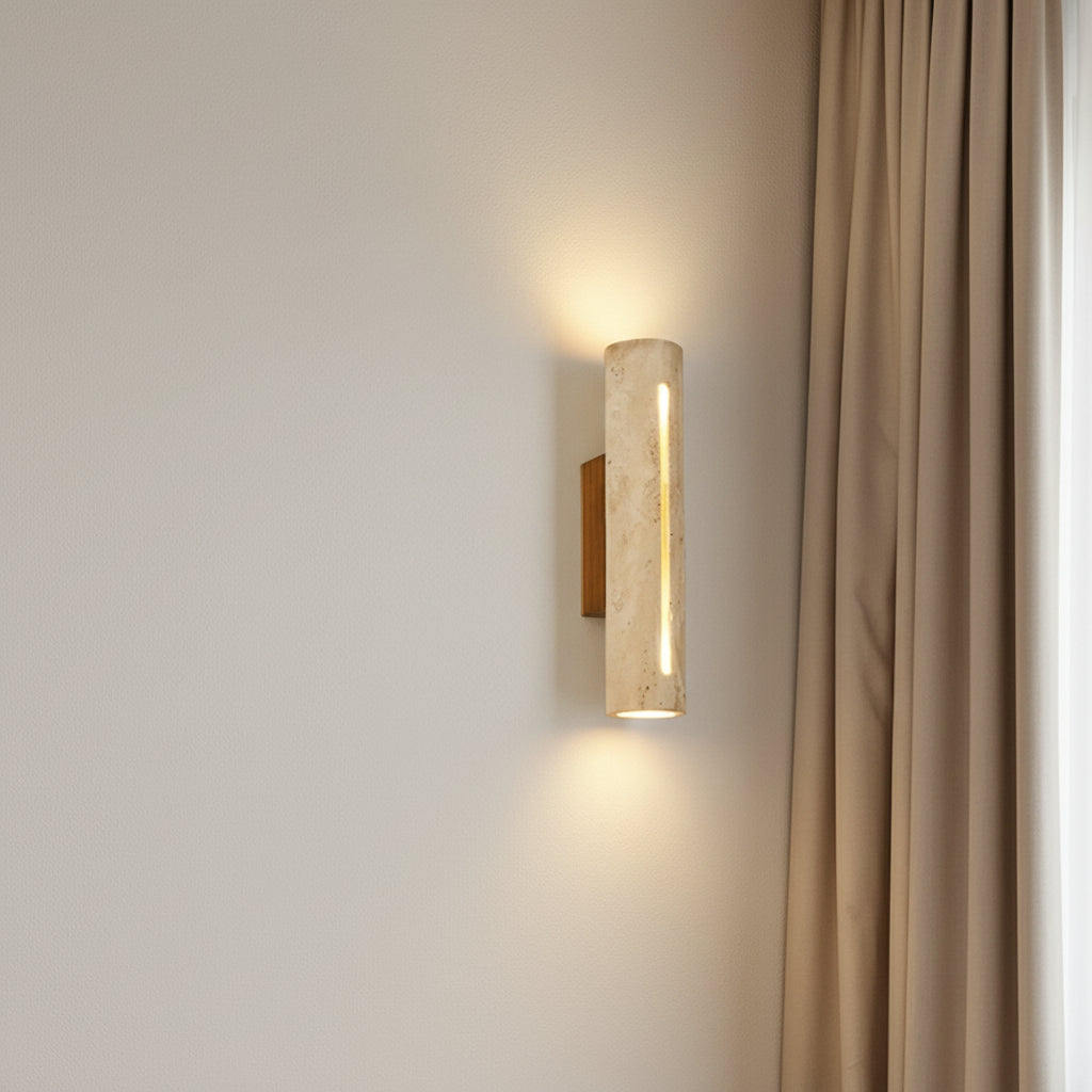 Beri travertine vertical-slot wall sconce with cylindrical diffuser, warm light glowing