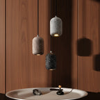 Concrete cylindrical pendant light cluster with speckled gray and black shades and black cords