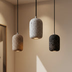 Concrete cylindrical pendant light with speckled gray and black shades, hanging on black cords