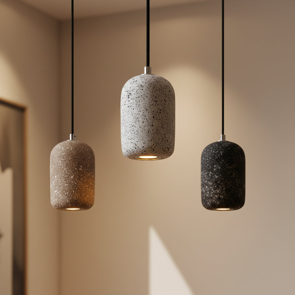Concrete cylindrical pendant light with speckled gray and black shades, hanging on black cords