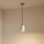 Wood-canopy terrazzo cylindrical pendant light with warm interior glow through cutouts.