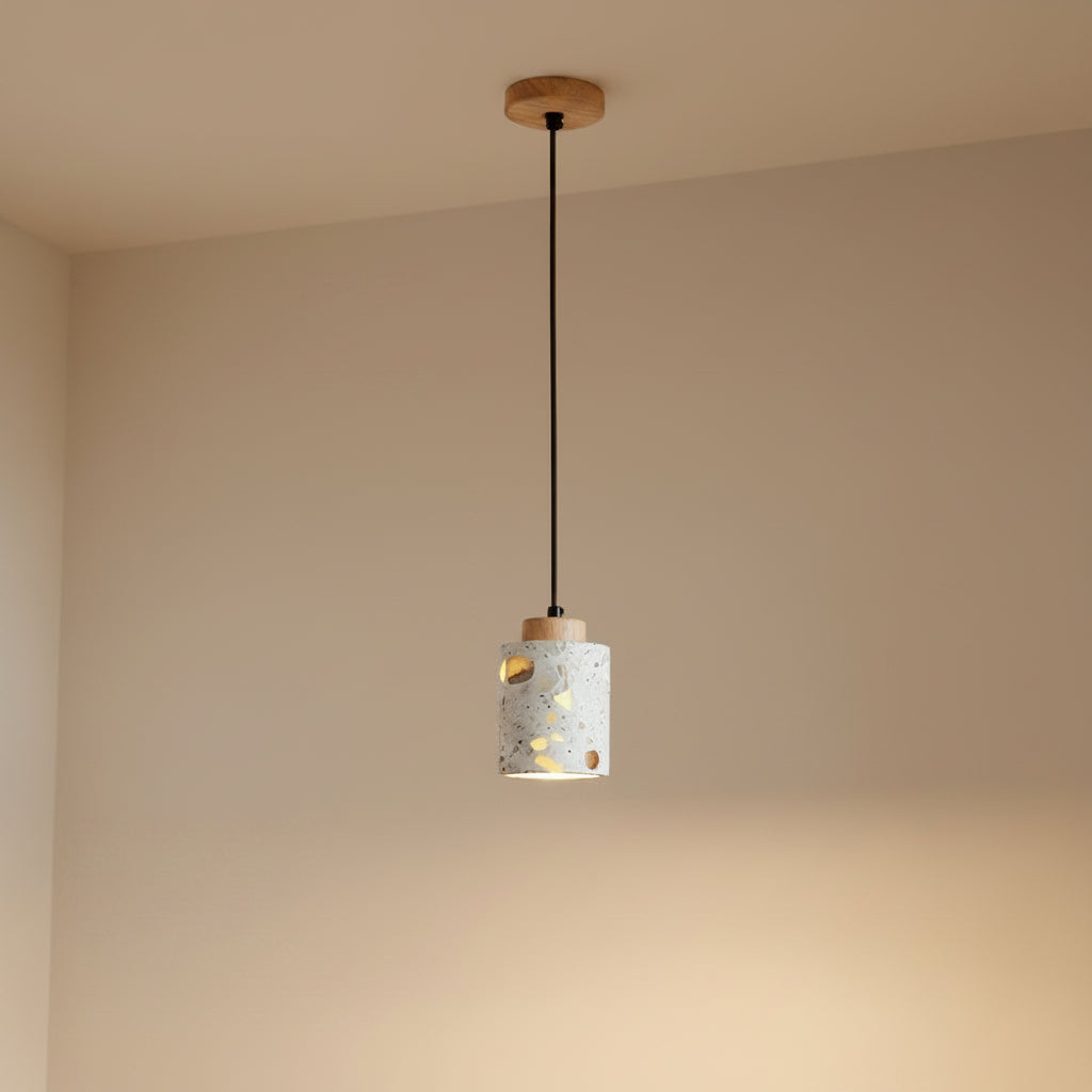 Wood-canopy terrazzo cylindrical pendant light with warm interior glow through cutouts.
