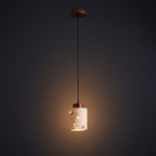 Terrazzo cylindrical pendant light shade hanging from a dark cord, warm glow visible.