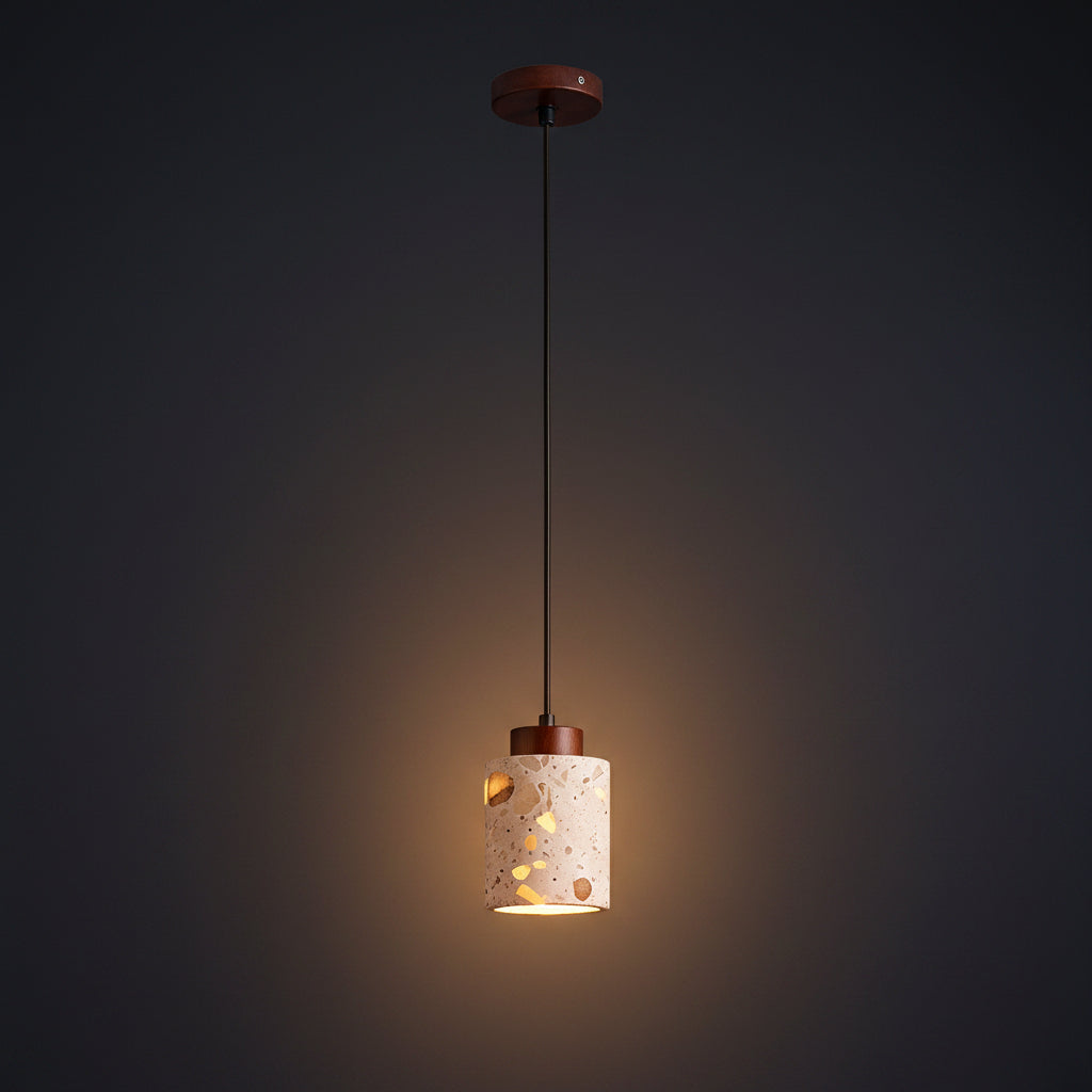 Terrazzo cylindrical pendant light shade hanging from a dark cord, warm glow visible.