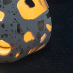 Terrazzo cylindrical pendant light shade with cutout pattern, lit with warm glow.