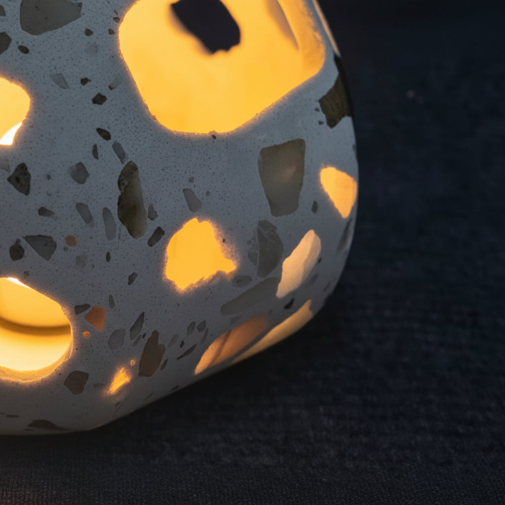 Terrazzo cylindrical pendant light shade with cutout pattern, lit with warm glow.