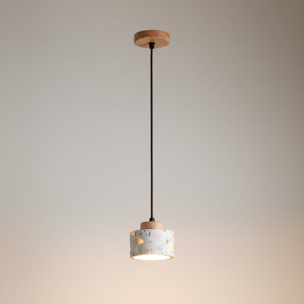 Terrazzo cylindrical drum pendant light with wood ceiling plate and hanging cord.